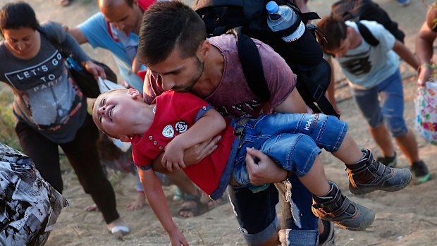 A young Syrian boy cries as his father carries him up a steep hill as they walk to a border crossing on the Greek and Macedonian border. 