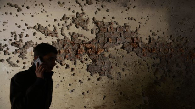 A Pakistani student walks past a bullet-riddled wall inside an army-run school that was attacked by Taliban militants.