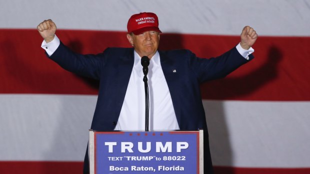 Republican presidential candidate Donald Trump raises his arms during a campaign rally.