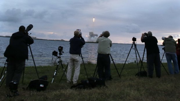Photographers follow the launch of the NASA Orion space capsule atop a Delta IV rocket, in its first unmanned orbital test flight, from the Space Launch Complex 37B pad.