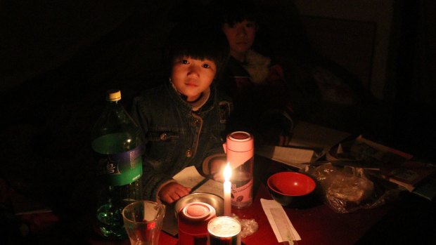 "My hands are OK but my feet are cold a little bit," says Xu Yuanyuan, 7, who is trying to study by candlelight.