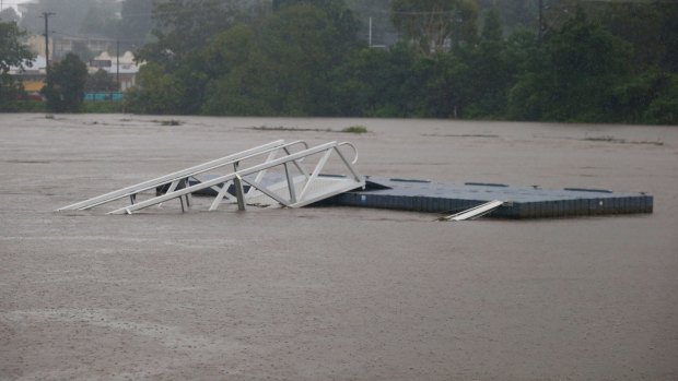A jetty is damaged as the Tweed River swell with floodwater.