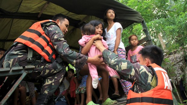 Military personnel evacuate young residents and their families living near the volcano.