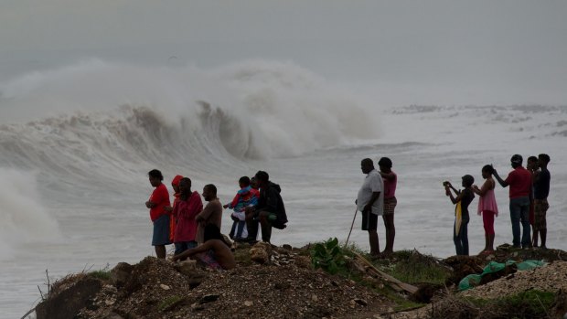 People stand on the coast watching the surf produced by Hurricane Matthew, on the outskirts of Kingston, Jamaica, on Monday. 