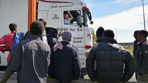 A truck driver on Thursday gestures at migrants as they try and board trucks bound for the United Kingdom in Calais, France. 