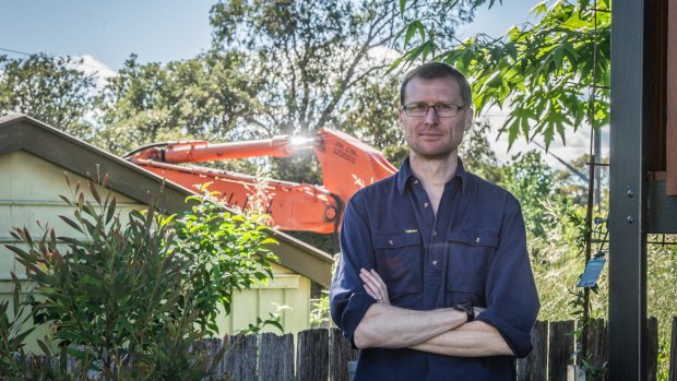 Brendan Pippen, in the backyard of his Duffy home, succeeded in persuading the government to demolish his neighbour's garage, in the background, which was used to store asbestos from the neighbour's Fluffy house.