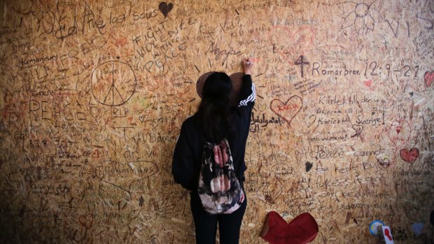 A woman adds her message to thousands of others on a wall at a Stockholm department store on Sunday, following the truck attack on Friday.