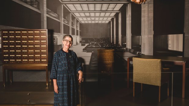 Director-General of the National Library of Australia, Dr Marie-Louise Ayres poses in front of a display of Fred Ward furniture representing a reading room from the 1960s.