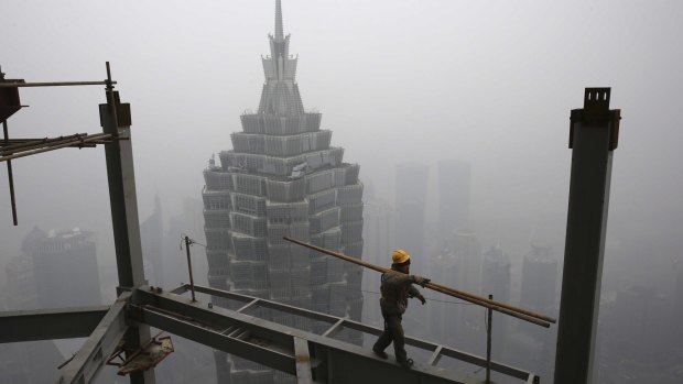 A worker carries steel bars on top of the construction site of Shanghai Tower.