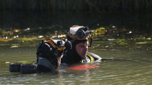 NSW police divers hold what appears to be a laptop submerged in an irrigation canal near Leeton, during their search for Stephanie Scott.