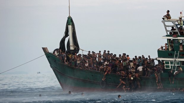 Rohingya migrants jump from their overcrowded vessel after a food drop. 