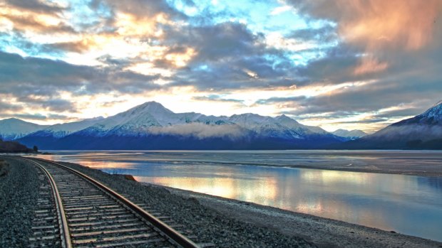 Train tracks and mountains are illuminated by the sunrise over Turnagain Arm in south central Alaska. 