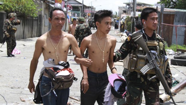 Two men who claim to be hostages are escorted to a waiting vehicle after being released from the hands of Muslim rebels in Zamboanga city in southern Philippines on September 17, 2013. 