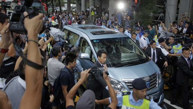 A van driving Donald Tsang is surrounded by photographers as it leaves a magistrates' court in Hong Kong on Monday.