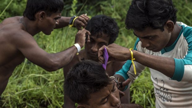 Rescued Rohingya men from Myanmar have haircuts at the confinement area in Kuala Langsa.