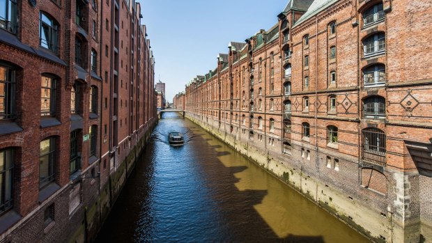 A tour boat passes along a canal in the Speicherstadt district of Hamburg, Germany.