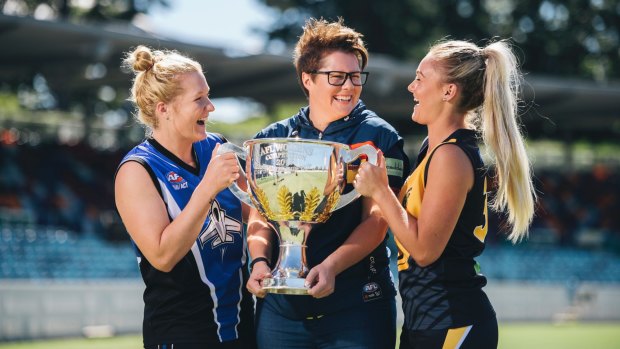 Women's ACT AFL players Britt Tully and Ella Ross with Adelaide coach Bec Goddard and the 2017 premiership cup.