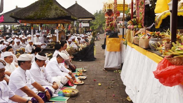 Balinese Governor I Made Mangku Pastika (fourth from left, front row) prays during the full moon ceremony.