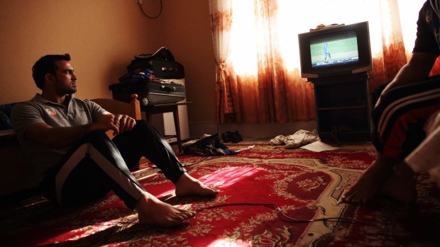 Afghan cricketer Samiullah Shenwari watches a cricket match on TV in Jalalabad