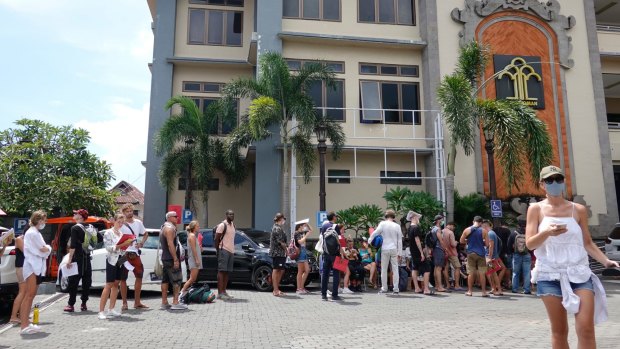 Tourists wear protective mask as they queue up outside the immigration office to extend their visas in Bali.