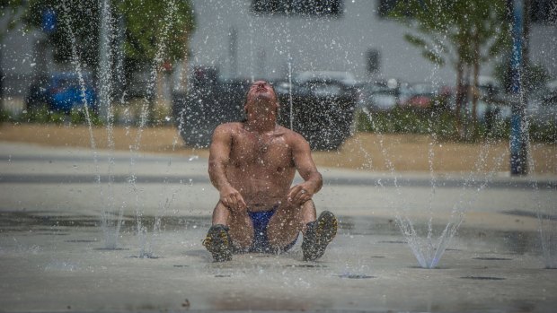 Craig Davis takes advantage of the new sprinkler fountain in Queanbeyan to cool off during the Summer hot spell.
