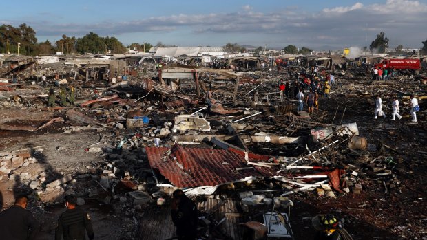 Firefighters and rescue workers walk through the scorched ground of Mexico's best-known fireworks market after an explosion.