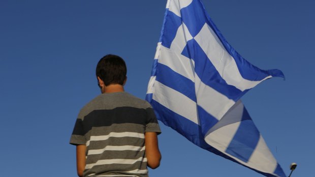 A young Greek boy waves his national flag. 