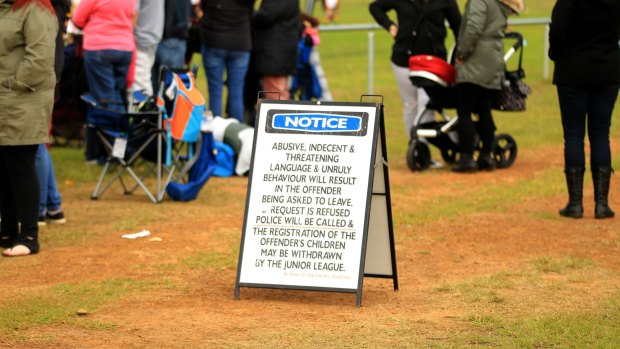 Parents and fans watch youngsters playing junior rugby league in Glenmore alongside signs advising unruly behaviour will not be tolerated.