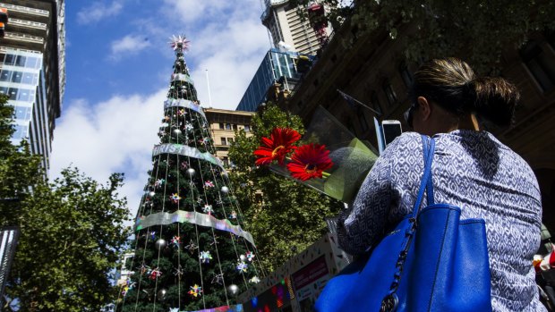 Not the centre of attention: A mourner passes the Martin Place Christmas tree. 