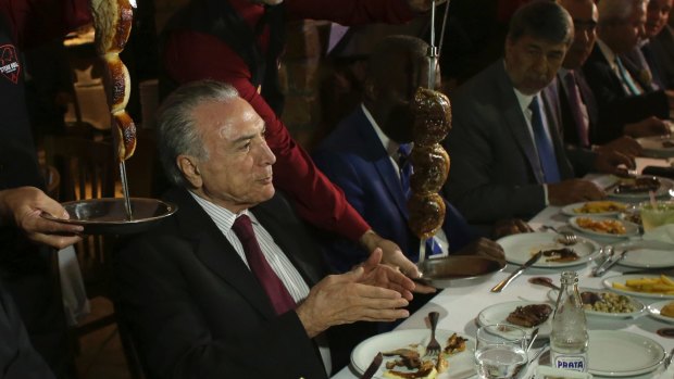 Brazil's President Michel Temer, left, hosts a dinner for diplomats at a traditional Brazilian barbecue restaurant.