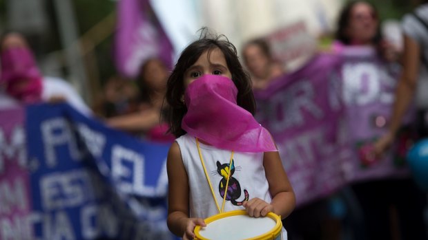 A girl with her face covered by a pink scarf marches marking International Day for the Elimination of Violence against Women, in Rio de Janeiro, Brazil, last month.