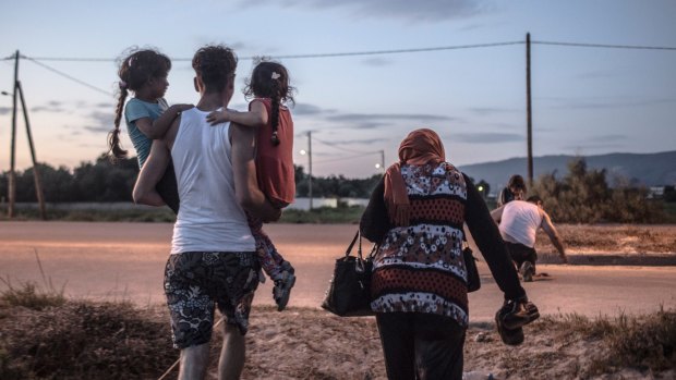 A Syrian refugee from Deir Ezzor carries his siblings ashore after arriving on the island of Kos in Greece.