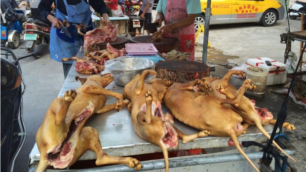 Vendors chop up dog meat for sale.