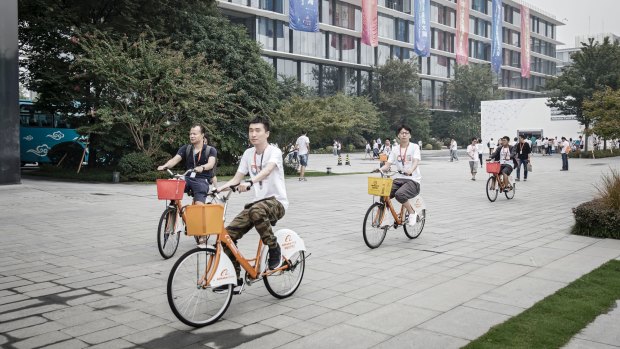 Employees ride their shared bikes though the grounds at the Alibaba head quarters in Hangzhou, China.