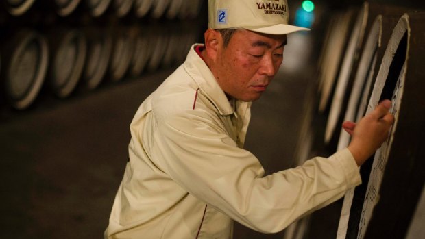 Senior general manager of the Yamazaki Distillery, Takahisa Fujii, knocks on whisky casks to check levels in the distillery's storage.