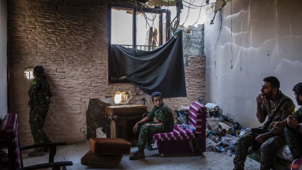 Male and female Syrian Democratic Forces fighters use a destroyed building as a base in western Raqqa.