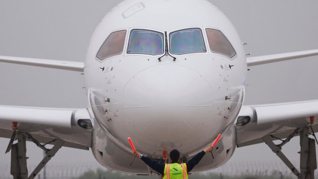 A member of staff gives signal in front of China's home-grown C919 passenger jet after it landed on its maiden flight at the Pudong International Airport in Shanghai.