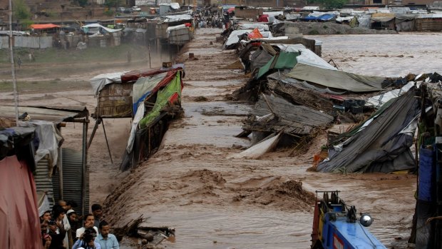 Villagers stand outside their homes during flash flooding on the outskirts of Peshawar.