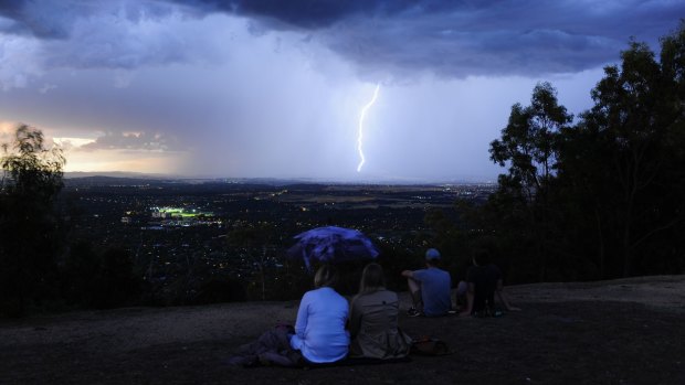People gather at the top of Mt Ainslie as a lightning storm can be seen across Canberra in December.