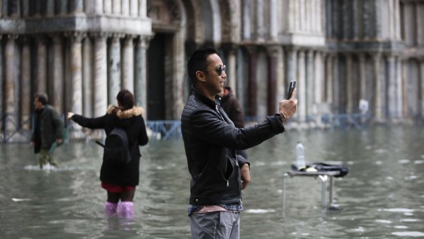 Tourists take pictures in a flooded St. Mark's Square.