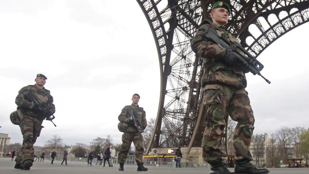 French army soldiers patrol under the Eiffel Tower.