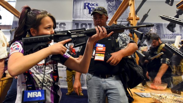 Shayanne Roberts looks at rifles in the trade booth area at the NRA convention.