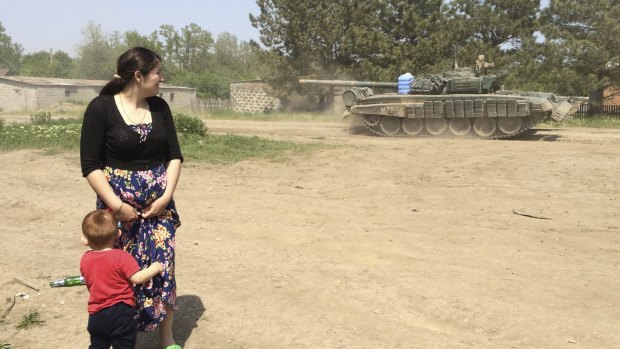 A woman with a boy looks at a tank as it drives through the Khutor Chkalova settlement on its way to a Russian military training ground near the Russian-Ukrainian border Rostov on May 26.