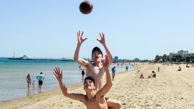 Mates enjoy the sunshine at St Kilda Beach on the grand final public holiday.