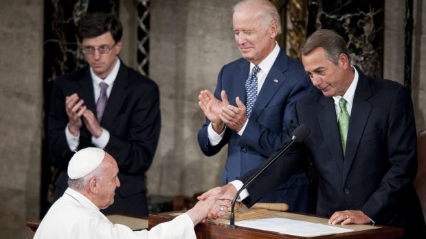 US Vice President Joseph Biden, centre, applauds as House Speaker John Boehner, right, greets Pope Francis as he arrives to speak to Congress in the House Chamber at the US Capitol.