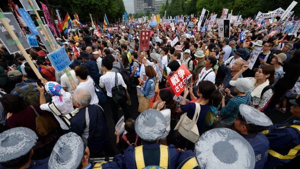Police take security measures as people protest outside the National Diet parliament building in Tokyo, on Sunday.