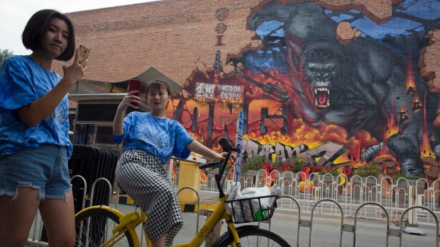 A woman takes a selfie near a mural for the movie <i>King Kong</i> in Beijing.