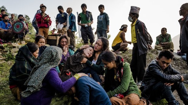 A mother is consoled on Tuesday after the funeral of her son, whose body was discovered under the rubble of houses destroyed during a massive earthquake in Nepal.