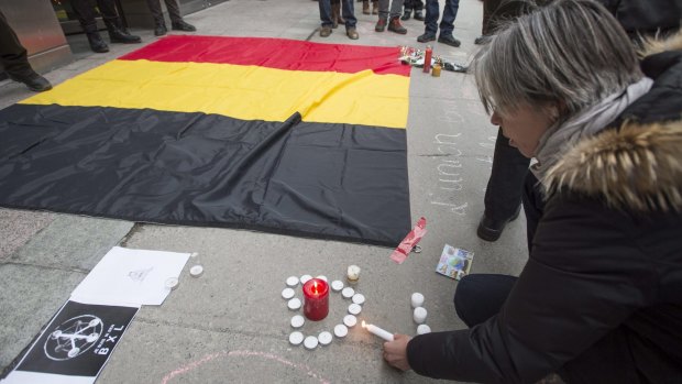 A woman places candles next to a Belgian national flag during a vigil on Wednesday in Montreal.