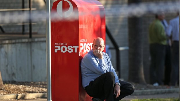 A man leans against an Australia Post letterbox at the scene of a shooting outside Warners Bay Post office on Wednesday afternoon.